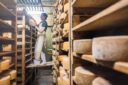 Une femme retourne des fromages dans une cave d'affinage