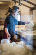 Une femme pr&eacute;pare des fromages dans un atelier de transformation.